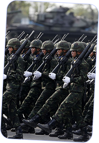 Soldiers in camouflage uniforms and helmets marching in formation while holding rifles with bayonets.